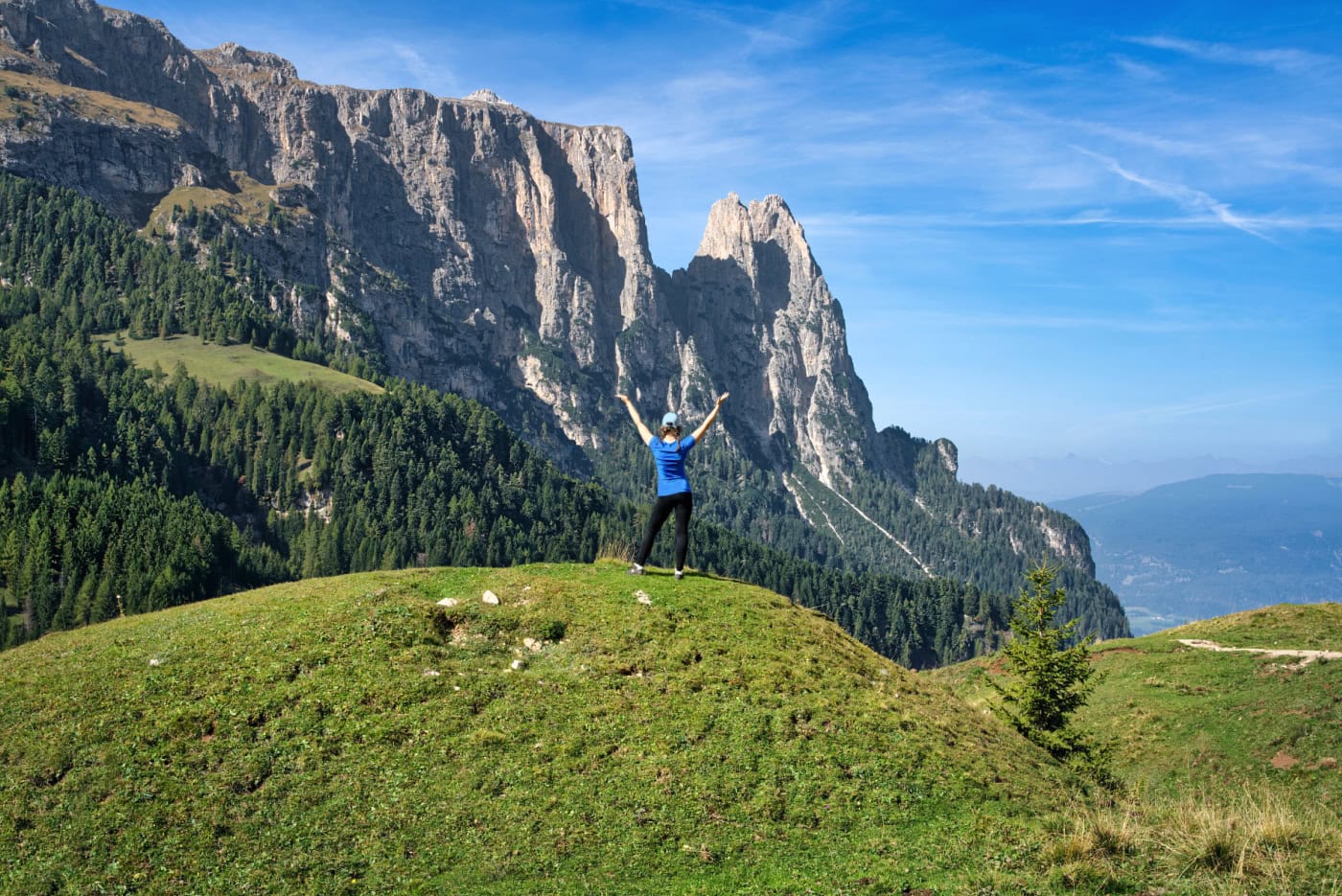 A woman hiker standing on an Aple di Siusi viewpoint for Schlern mountain.