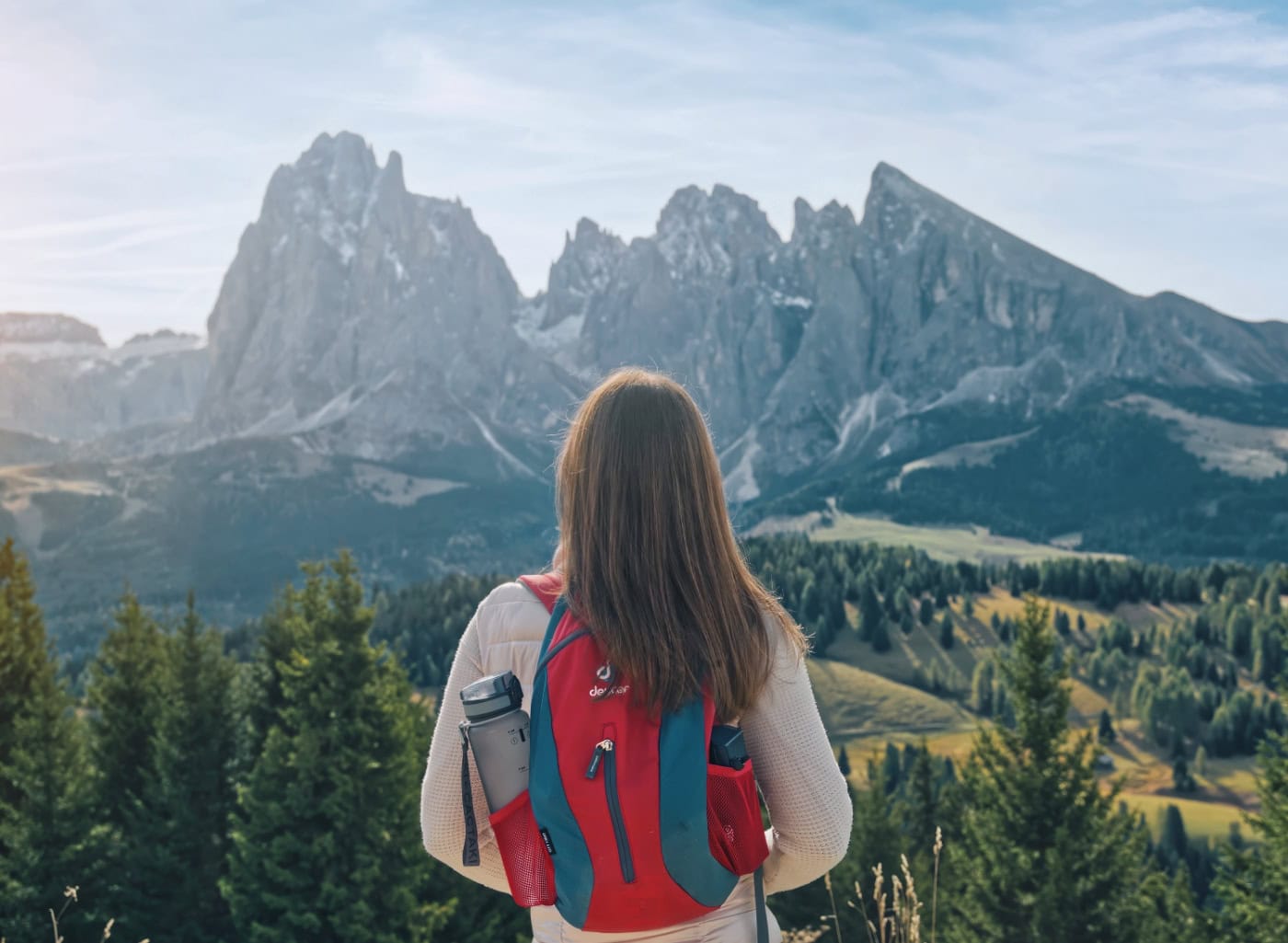 A woman hiker standing on Alpe di Siusi looking at the Sassolungo massif.
