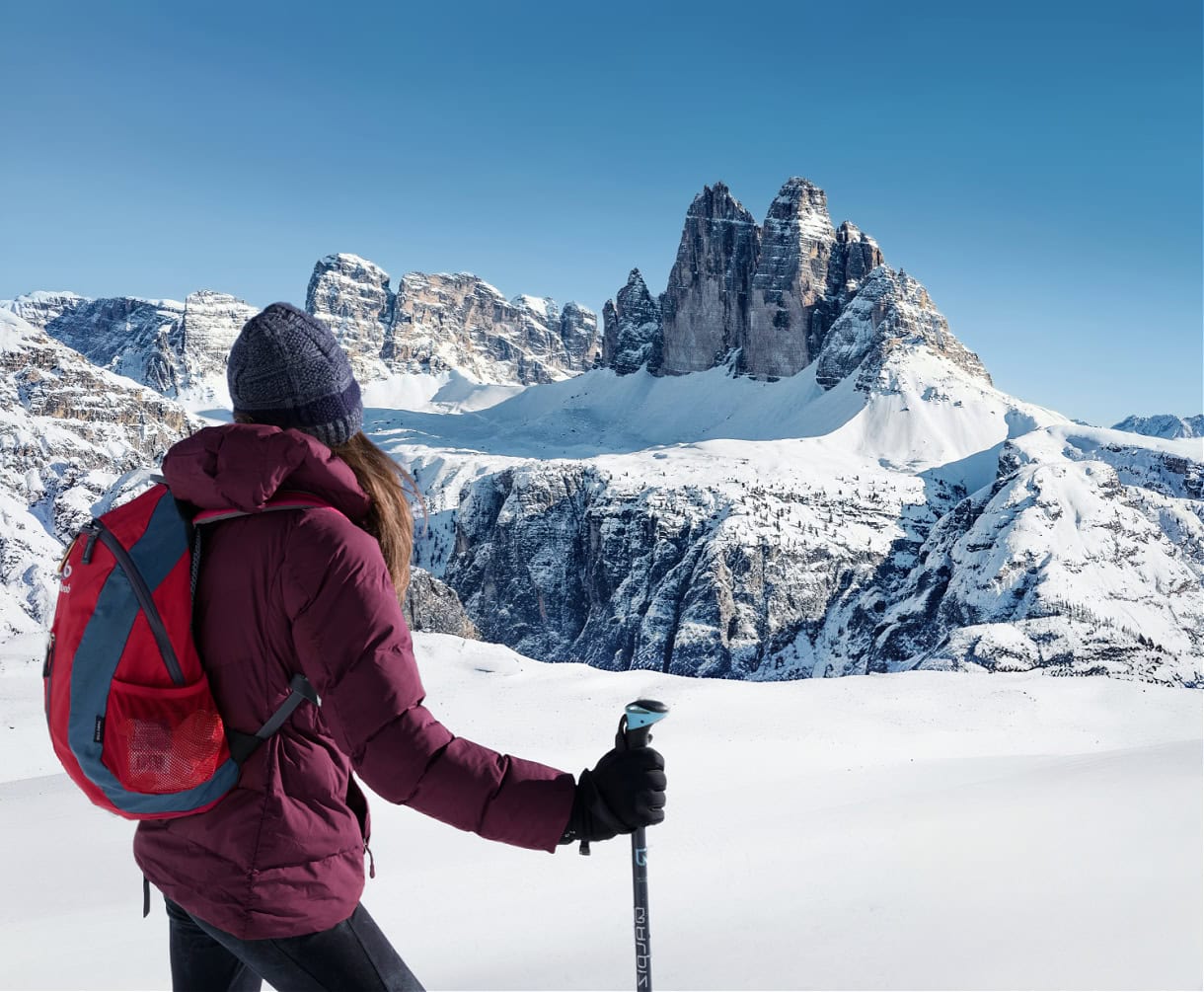 A girl hiker admiring the Tre Cime di Lavaredo from Monte Specie in the winter. 