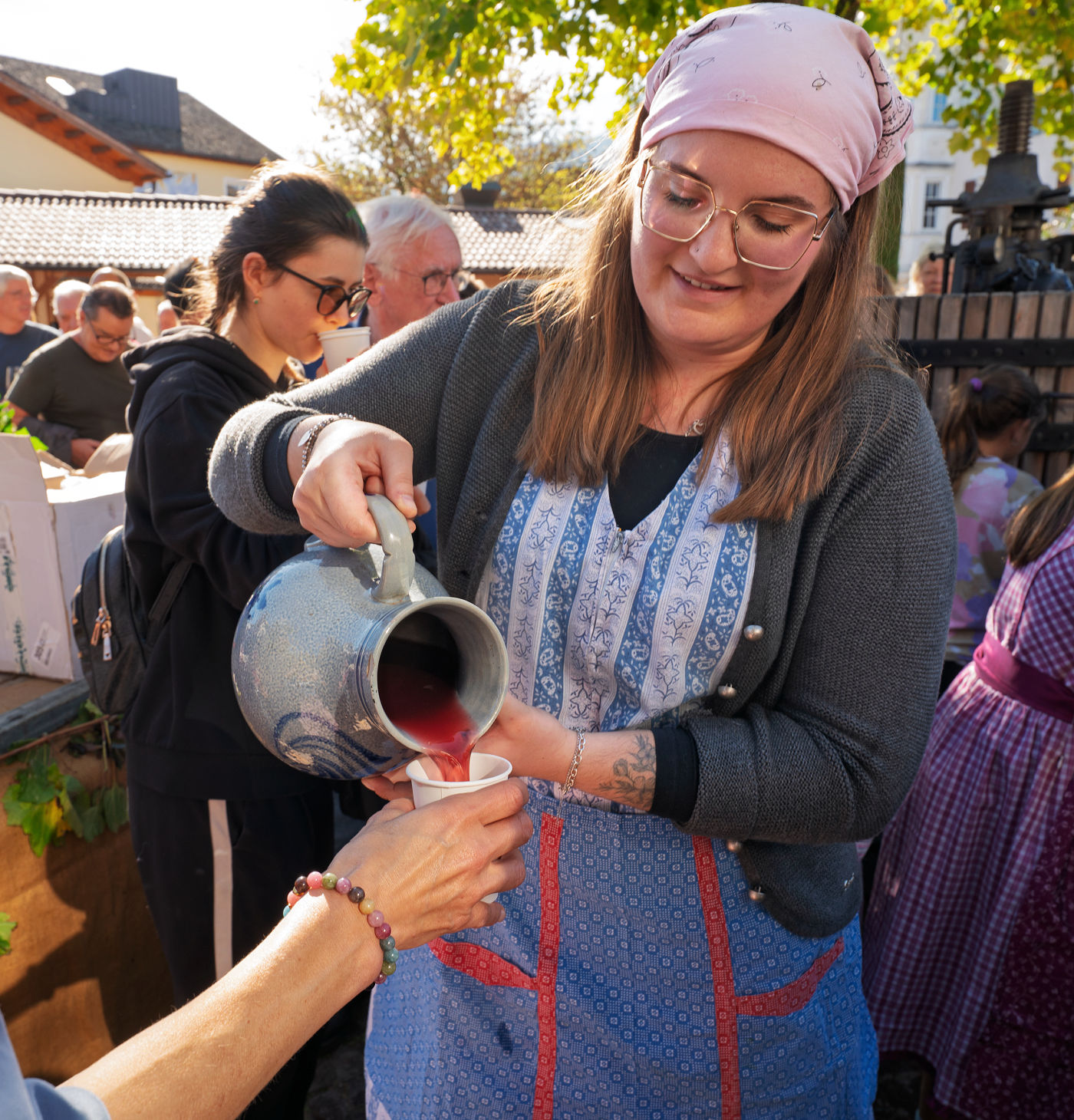 From Vine to Village: Raise a Glass at South Tyrol's Last Load of Grapes Festival 13 Fresh grape must being poured by a woman at Last Load of Grapes Festival in Girlan.