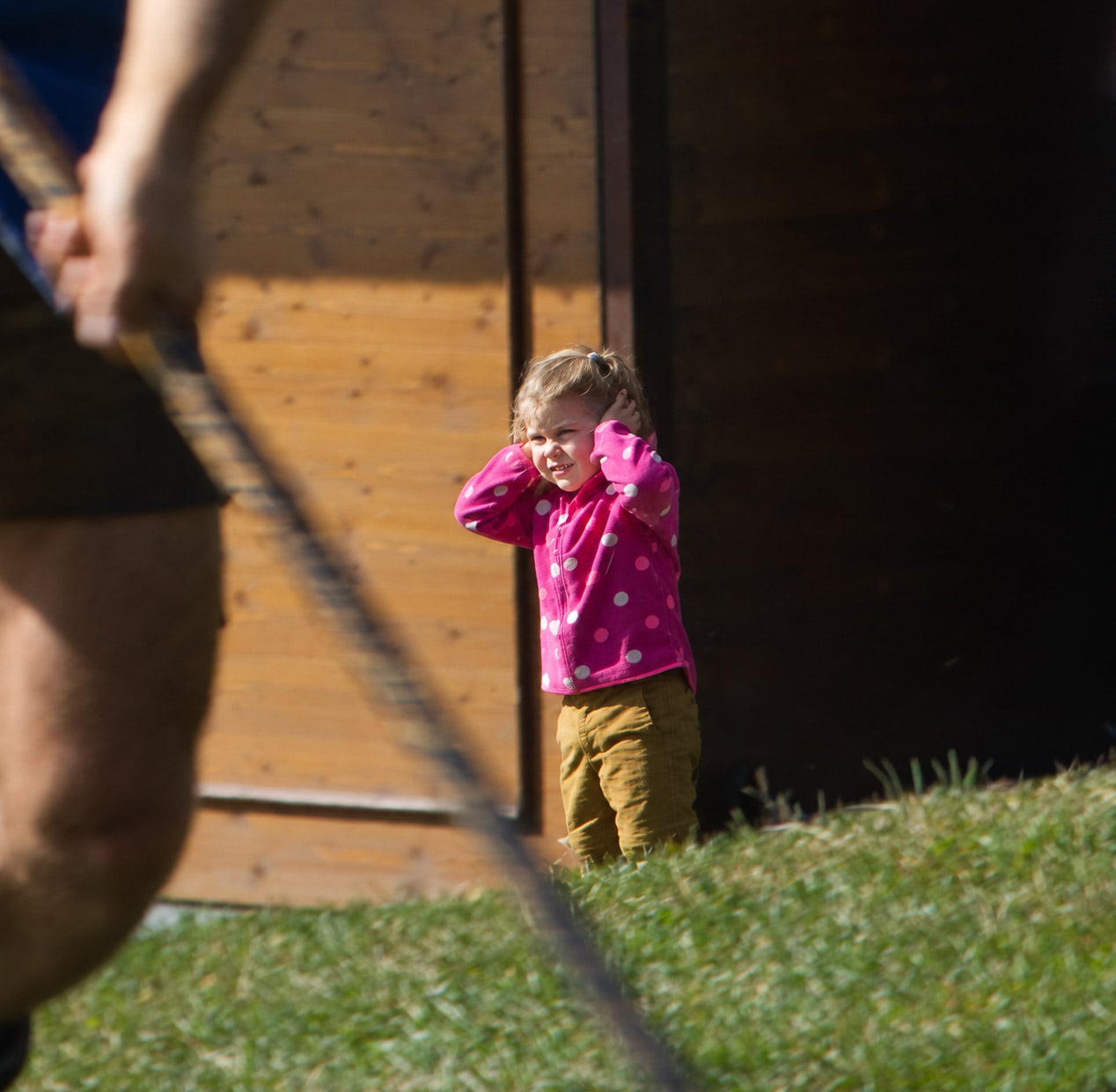 A child covering her ears as a Goaslschnöller gets ready to snap his whip.
