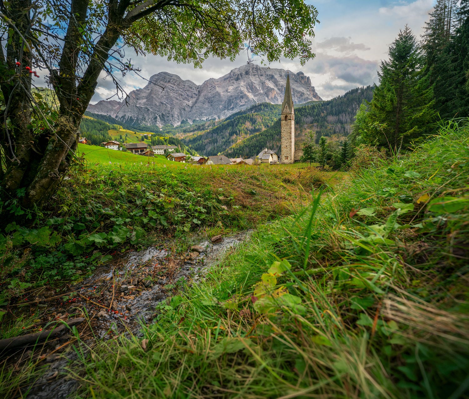Discover La Val: What to See & Do in Alta Badia's Most Beautiful Mountain Village 11 An old church tower above the "Les Viles" in La Val with the Dolomites in the backround.