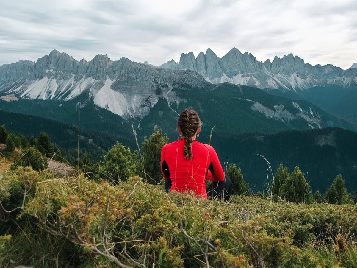 A female hiker on Plose admiring the view of the Dolomites.