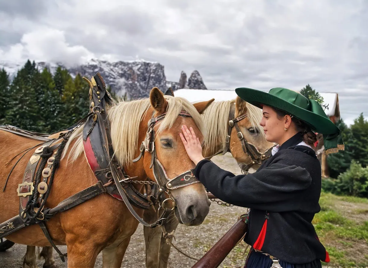 A member of the San Martin de Tour band petting a horse during Almabtrieb on Sesier Alm (Alpe di Siusi).