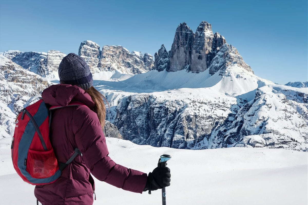 A woman hiker admiring Tre Cime di Lavaredo in the Dolomites during winter. 